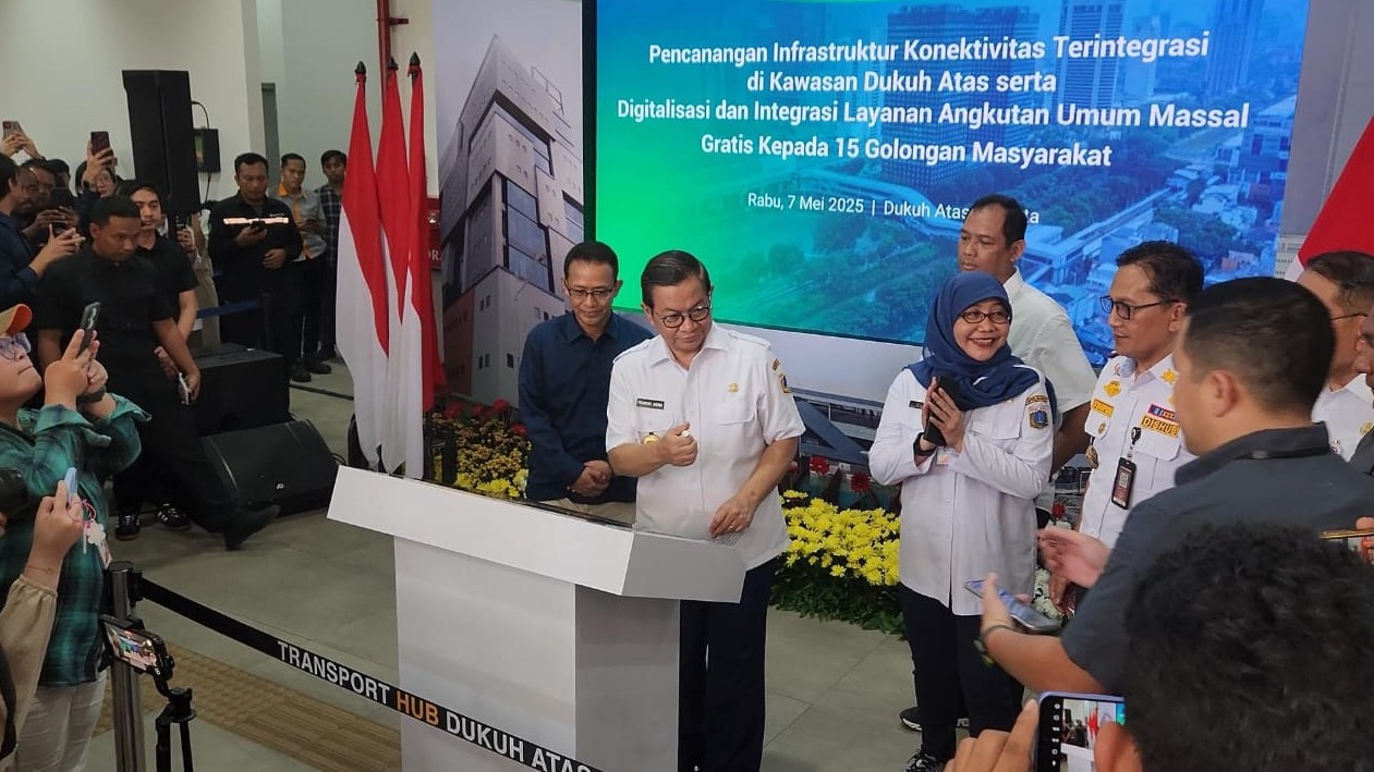 Sekumpulan undangan acara dan wartawan mengelilingi podium acara. Gubernur Jakarta Pramono Anung berada di tengah-tengah podium.
