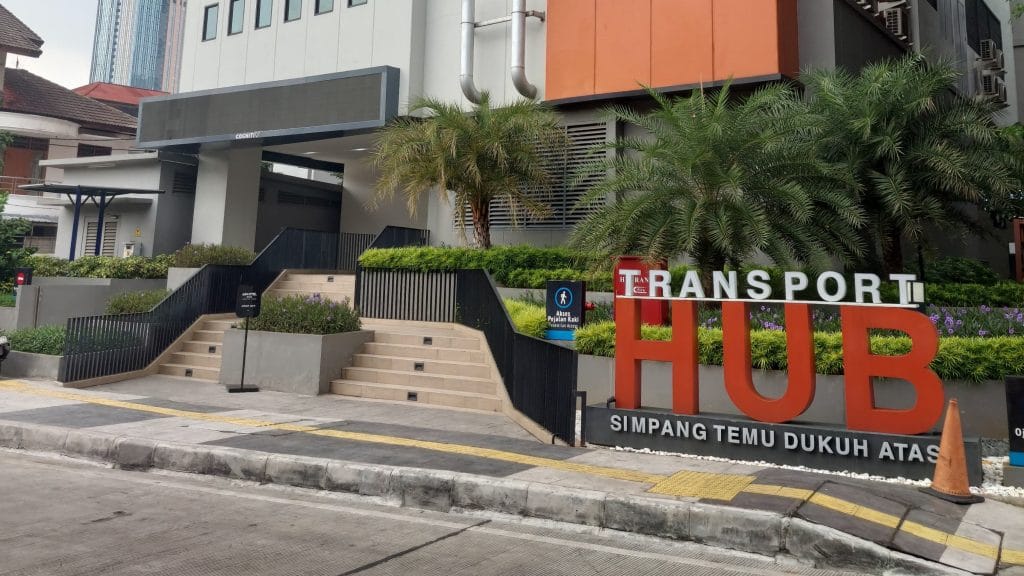 Tampak depan gedung Transport Hub Dukuh Atas dengan instalasi signage bertuliskan "TRANSPORT HUB SIMPANG TEMU DUKUH ATAS"