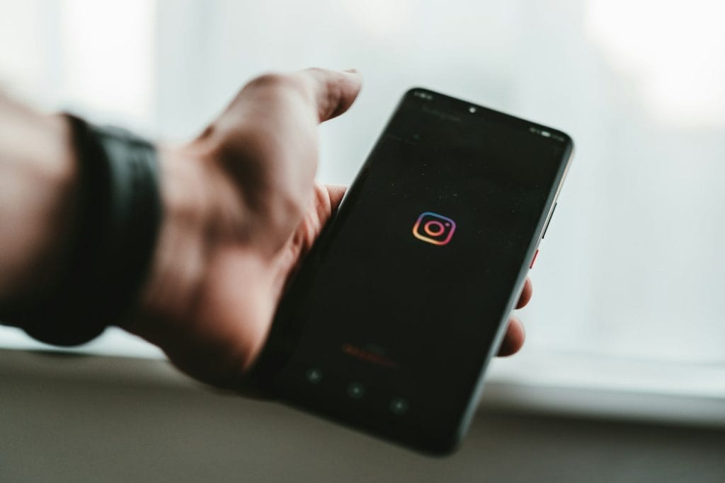 person holding black android smartphone showing Instagram app opened.
