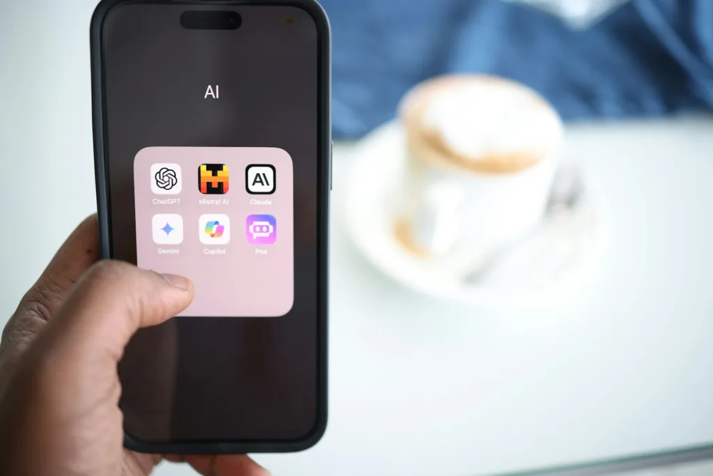 a person holding a cell phone in their hand with AI apps shown in the home screen