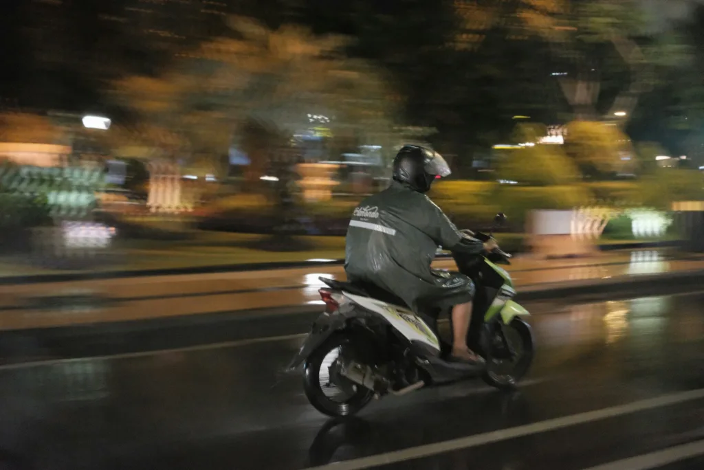 A man riding a motorcycle down a street at night
